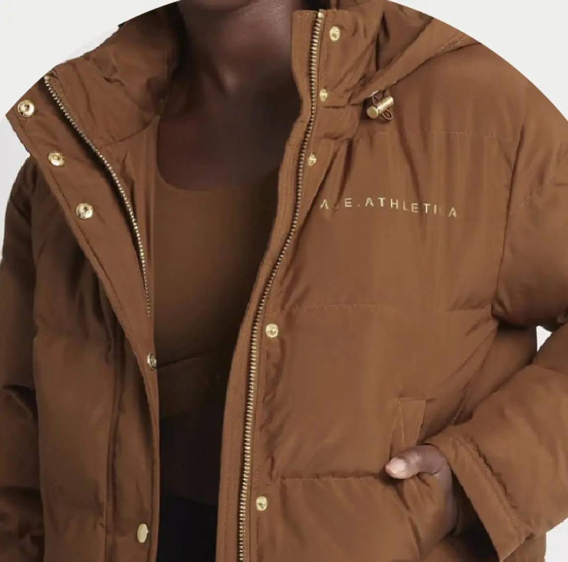 Woman wearing brown sports bra under a puffy brown AJE Athletica Jacket